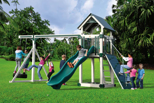 Children playing on a playground set with a green slide and swings in a park.