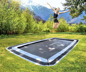 Person jumping on a trampoline in a grassy area