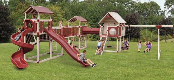 Children playing on a large vinyl playset with multiple slides, swings, and a clubhouse in a backyard