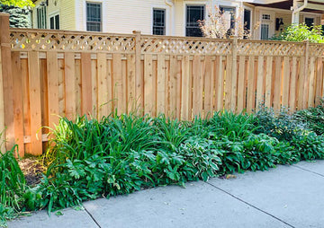 Cedar shadowbox privacy fence with a diagonal lattice top running along a perennial garden bed beside a North Shore home