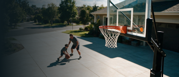 Two people playing basketball on a driveway hoop
