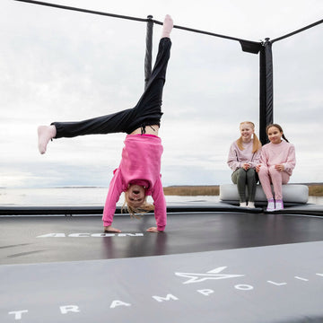 Children playing on a trampoline with one doing a handstand
