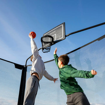 Two children playing basketball on an outdoor court 