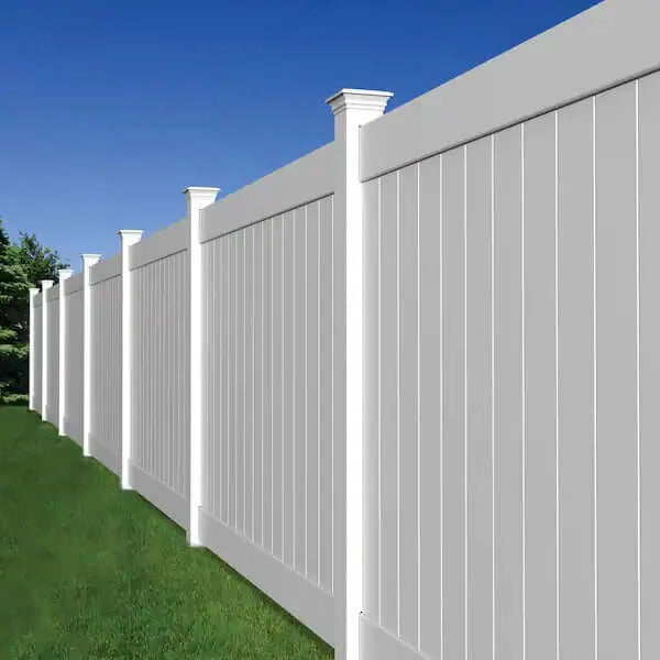 White vinyl privacy fence with decorative post caps installed along a grassy yard